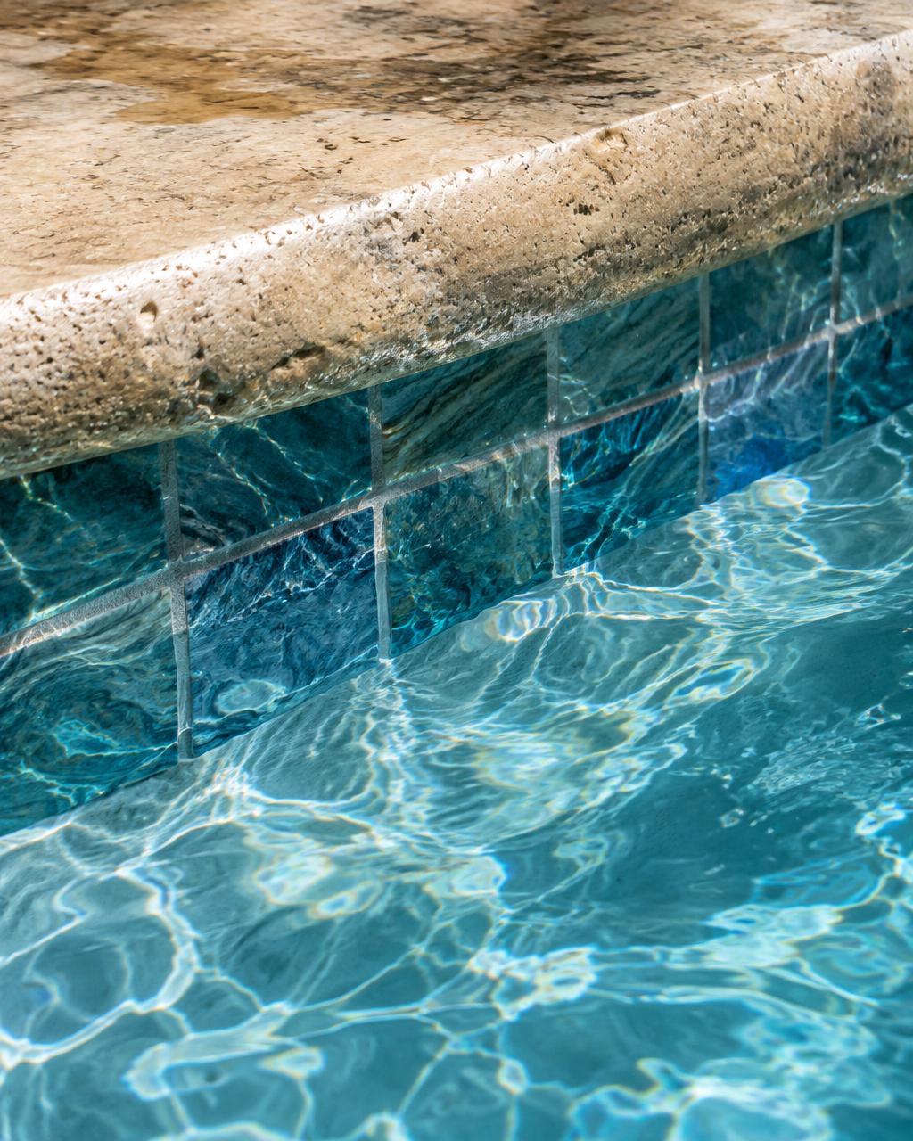 Waterline tile beneath travertine coping